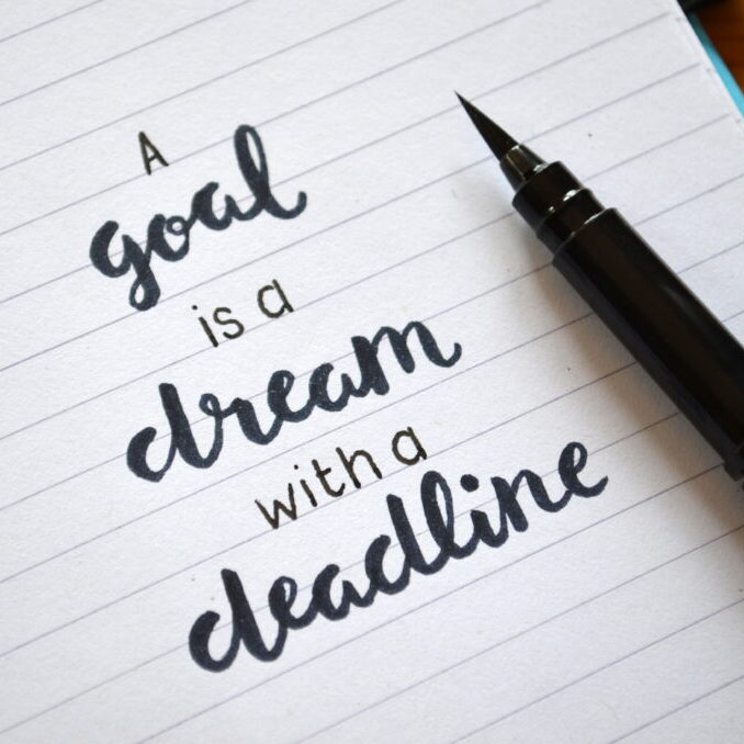A GOAL IS A DREAM WITH A DEADLINE written in notebook on desk